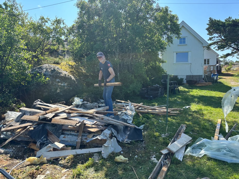 En mann som rydder materialer og skrot etter riving av et uthus på Pynten på Kråkerøy.