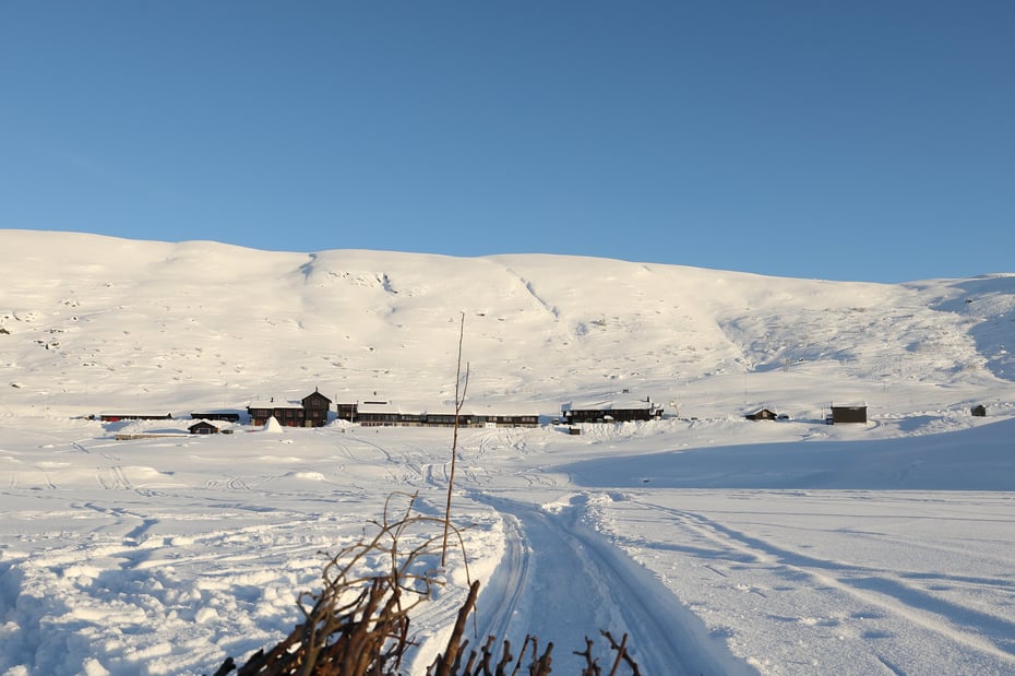 Haukeliseter Fjellstue. Det er en god del snø og solen skinner. Det er sccoterspor da de setter opp kvist. 
