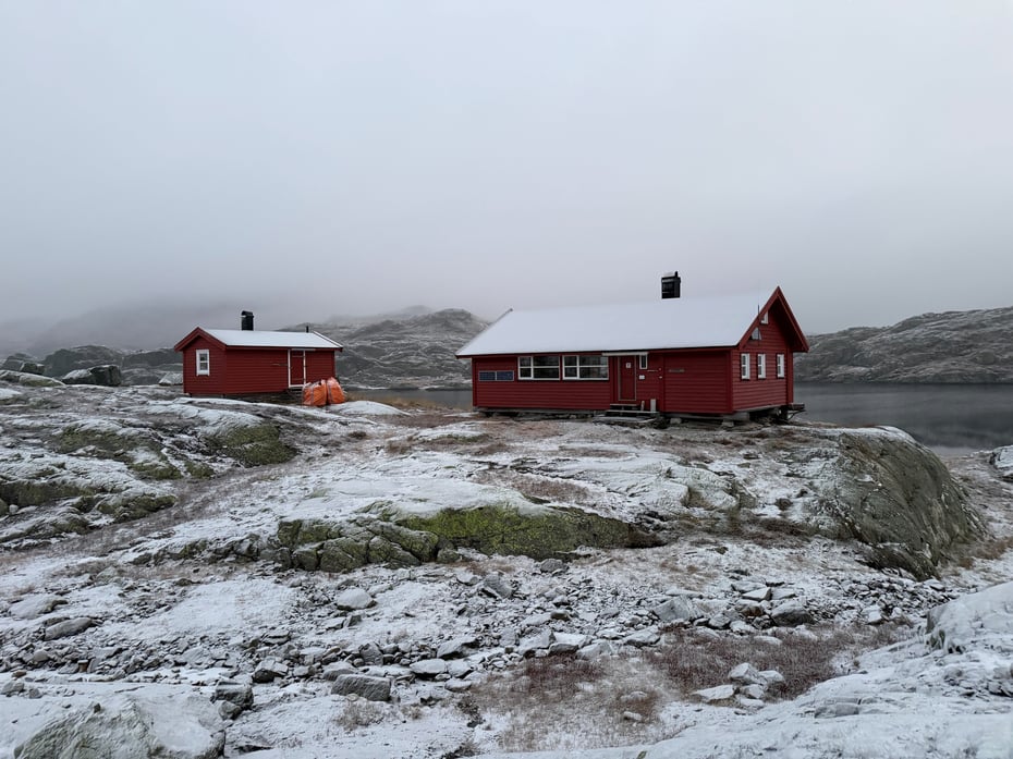 Krossvatn. 2 røde hytter. Det er litt snø på bakken og viser at vinteren nærmer seg.