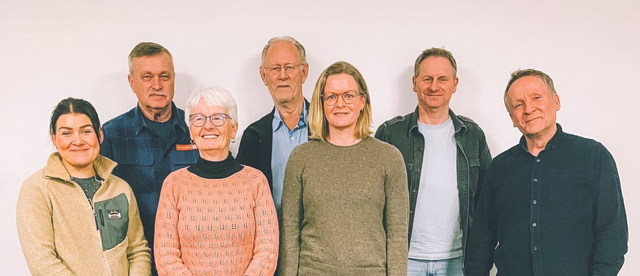 Tre damer og fire menn står oppstilt foran en hvit vegg.