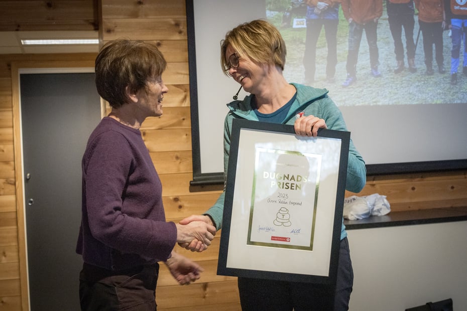 En kvinne overrekker en plakett til en annen kvinne.