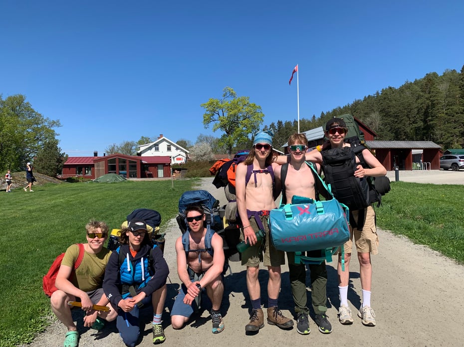 Gruppebilde av seks gutter med ryggsekker på. Himmelen er blå, alle har på seg solbriller og smiler.