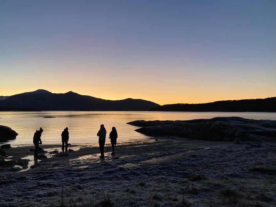 Fire personer og solnedgang på ei strand