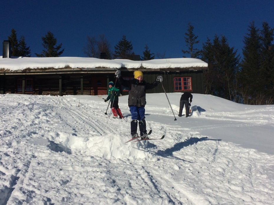 Barn leker på ski utenfor hytta