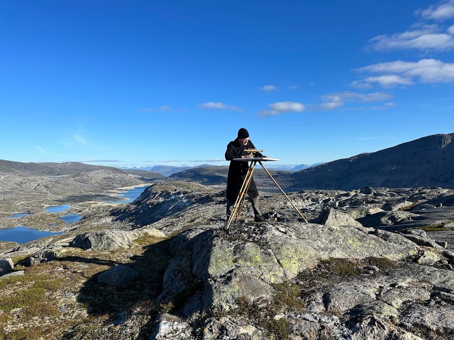 Mann ved toppen av Langvassfjellet som studerer kartskiva