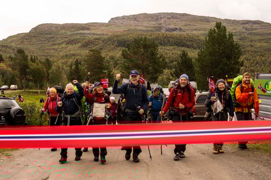En gjeng med glade vandrere bryter ei målsnor utformet som et norsk flagg