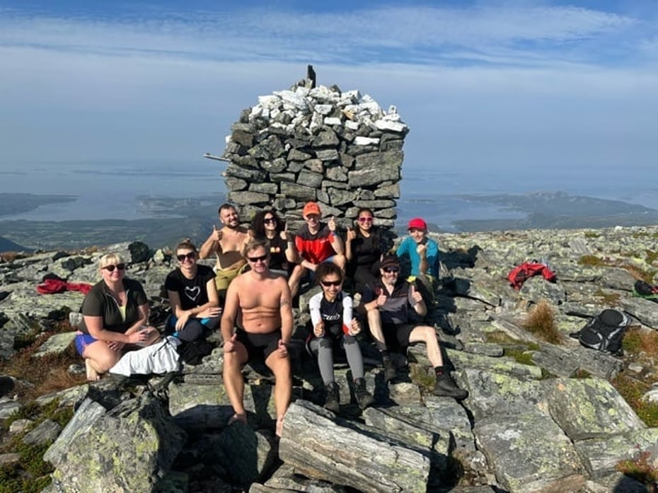 Bilde av varde på toppen av fjellet Storøra med turdeltakere sittende rundt.