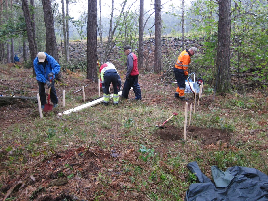 Mennesker som graver i skogen for å bygge en gapahuk
