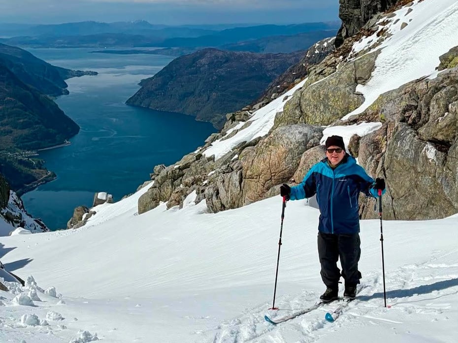 Mann med ski står foran fjordutsikt