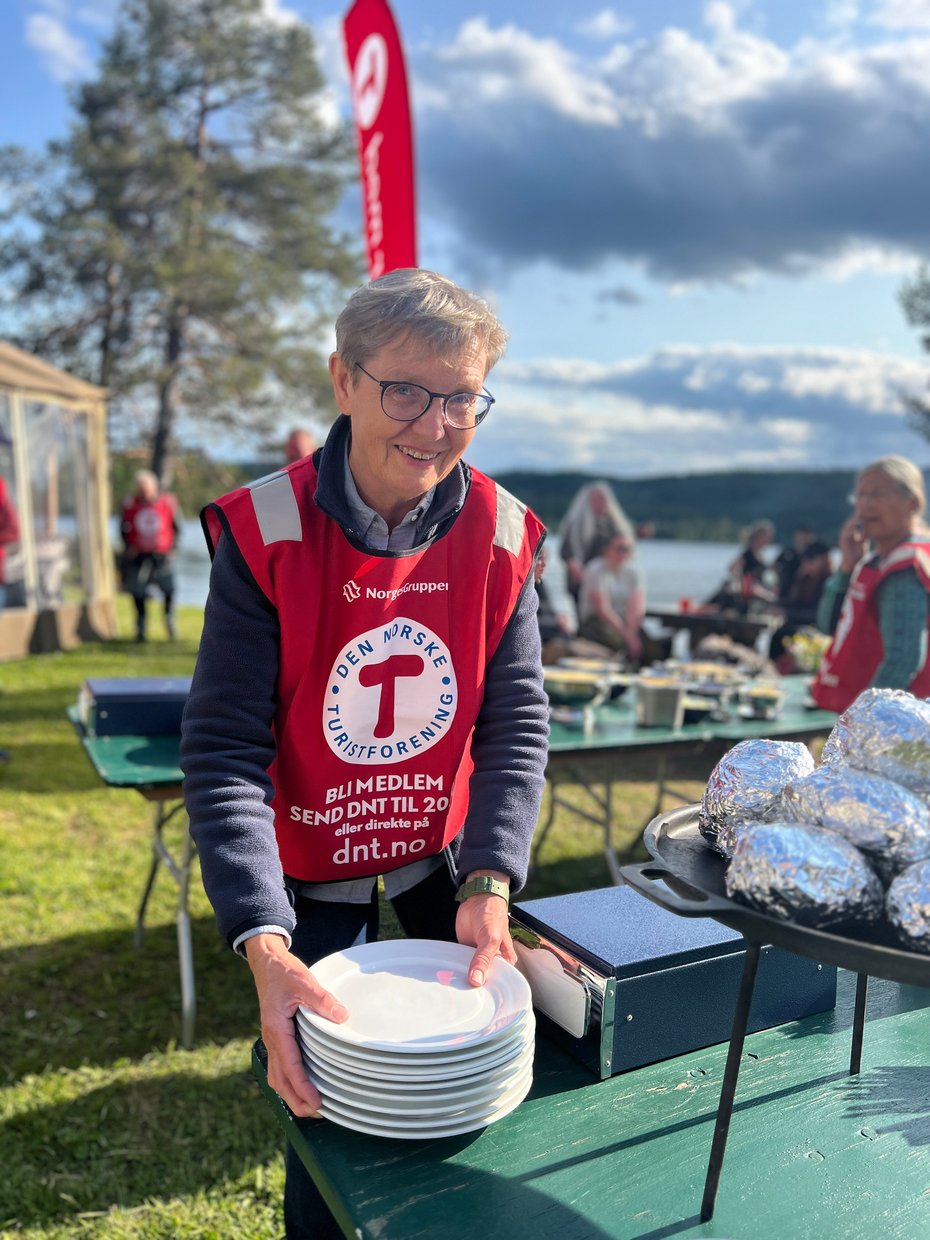 Kvinne i DNT-vest som dekker på bord til servering