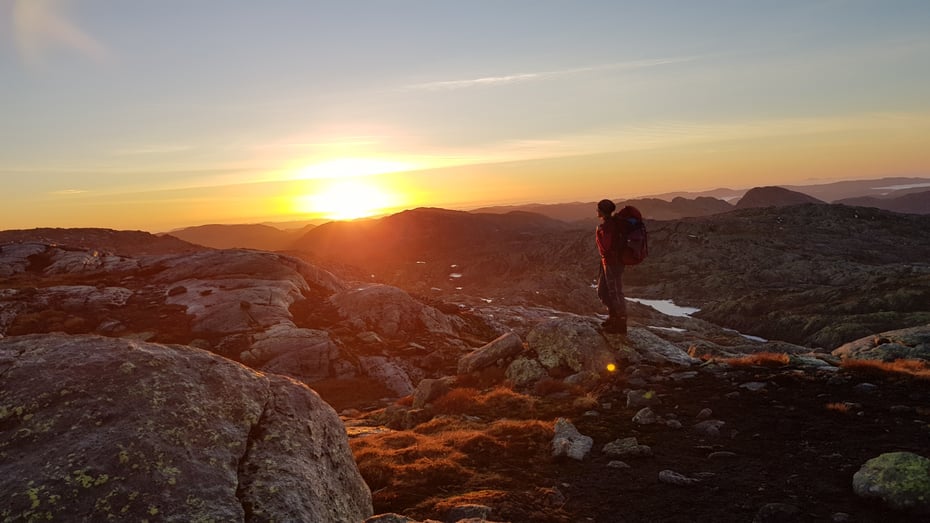 Turgåer i vakkert fjellandskap i solnedgang.