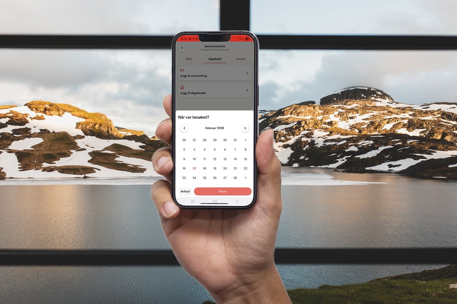 Mobil med DNT-app foran hyttevindu