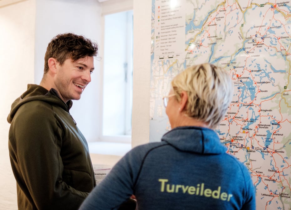 Mark Watson får tips om kart og turveiledning fra Kaja Raa Storaker på Tursenteret i Stavanger.
