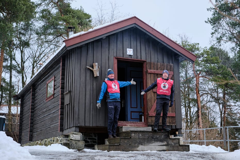 To frivillige fra DNT ønsker velkommen inn i DNT-hytta på Norsk Folkemuseum