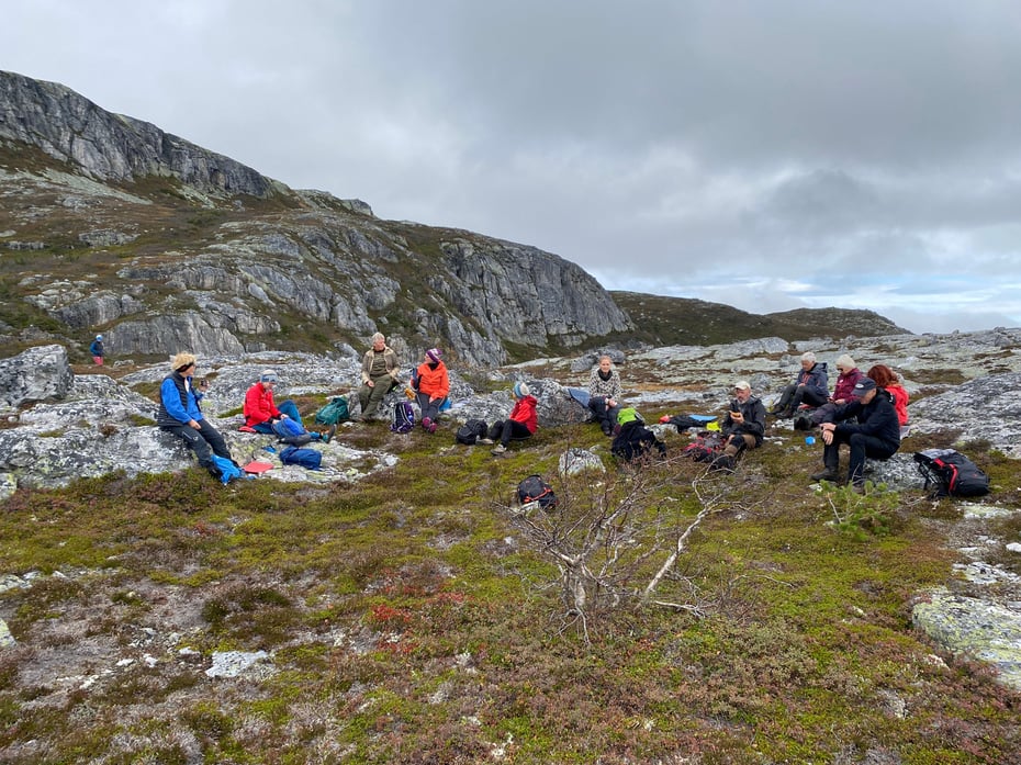 Mennesker sitter på et fjell og spiser niste
