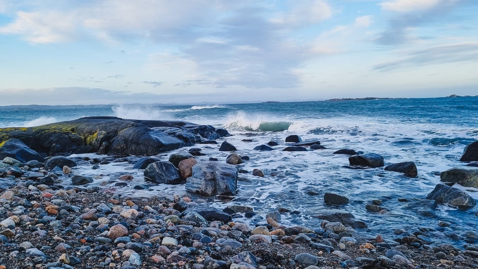 Rullesteinstrand og bølger som skvulper mot land