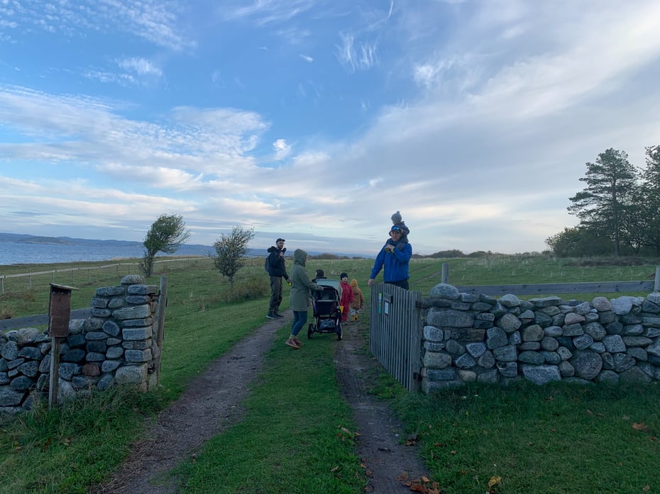 Familie med barnevogn på tur langs en strand ved sjøen
