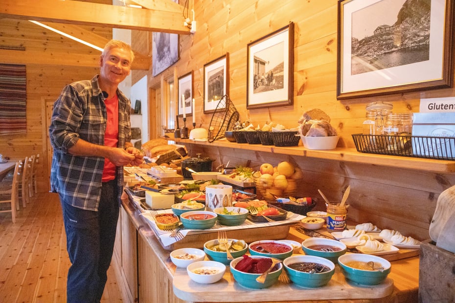 Bestyrer Halvor smiler til kamera mens han gjør klar frokostbuffeten.