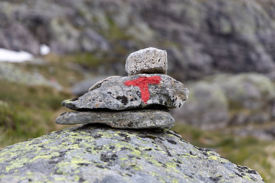 Rød T malt på varde bestående av tre steiner.