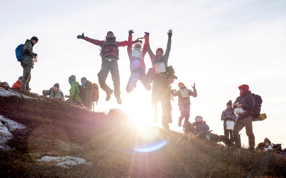 En gruppe ungdommer hopper av glede på en fjelltopp