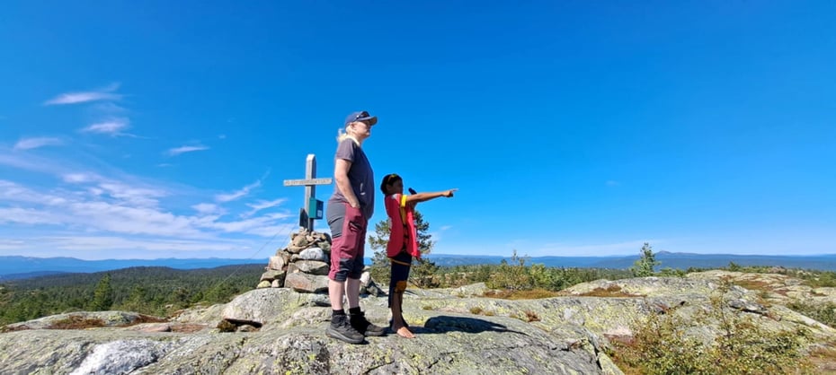 En voksen og et barn står på en fjelltopp og skuer utover