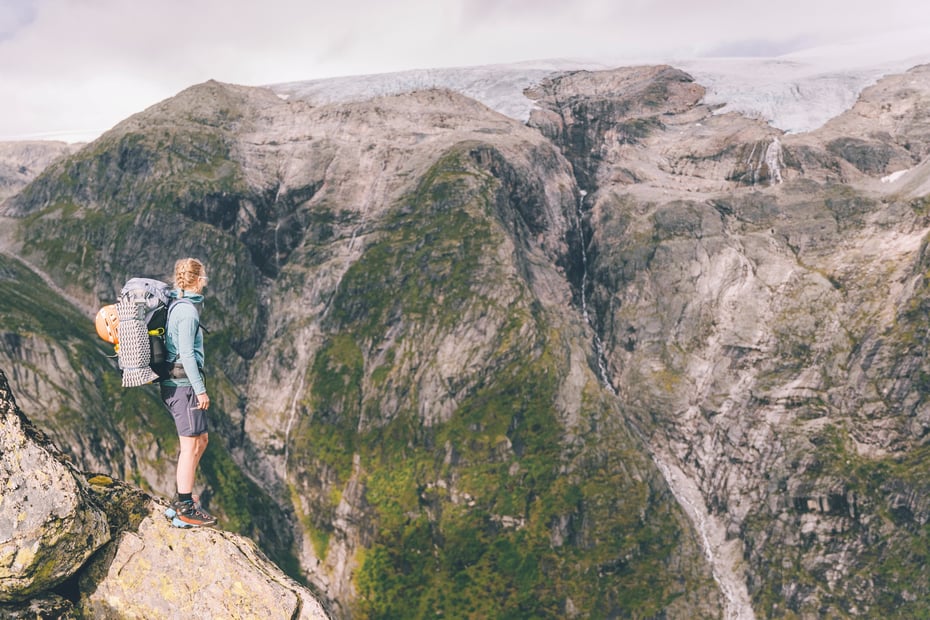 Dame står på fjell og ser utover landskap