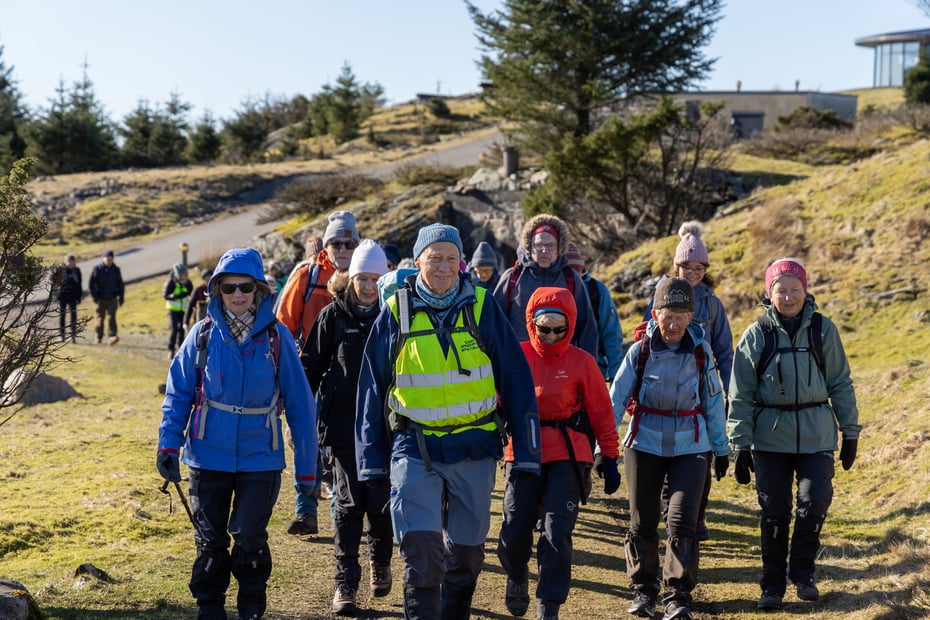 En gruppe seniorer på tur, men mannlig turleder i midten.