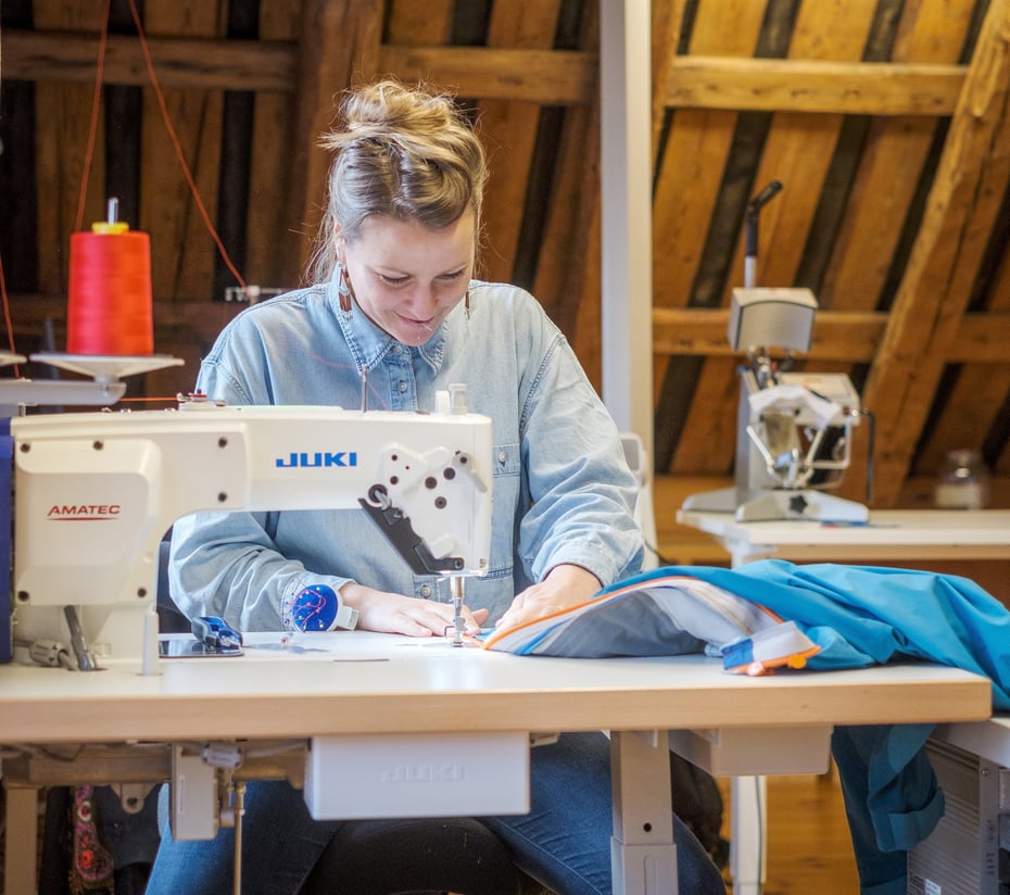 Bilder fra ReTuren syverksted. Bærekraft, gjenbruk, miljøvett, søm, rød tråd, saks, nål og tråd, symaskin, glidelås. Eleonore Hatfield på bildet.