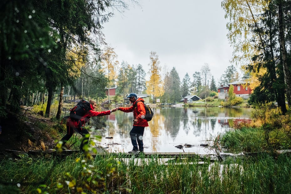En mann som er på tur og balanserer på en planke, får hjelp av en annen turgåer.