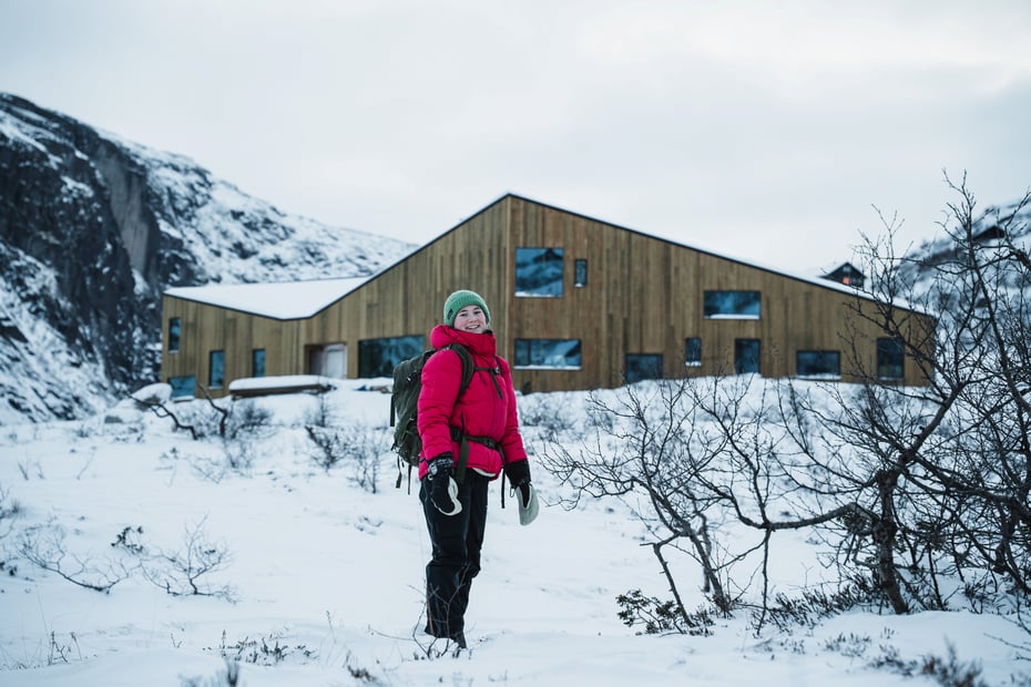 En jente med rød jakke står foran en helt ny hytte.