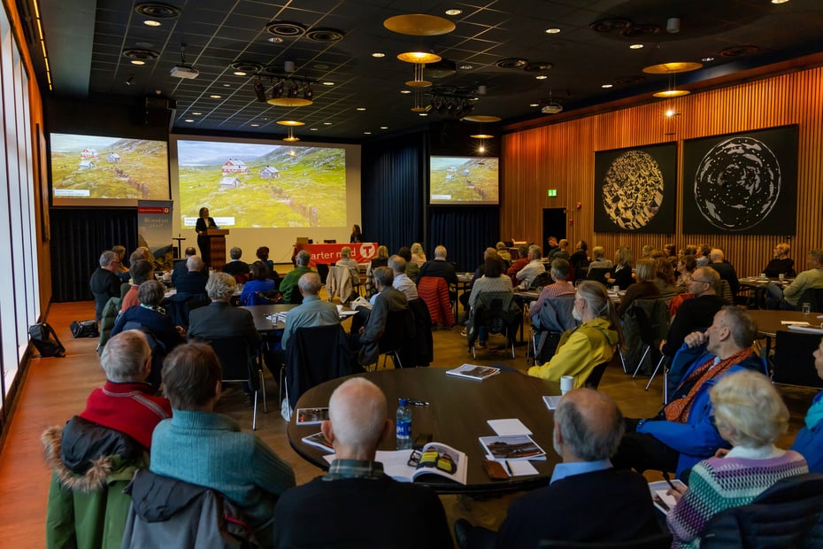Masse folk i stor sal og en dame på scenen.