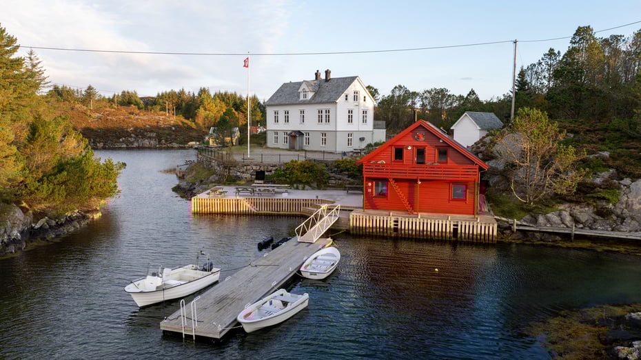 Stor, hvit hytte med flytebrygger og båter