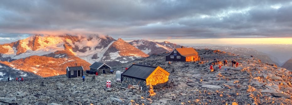 Solnedgang og liv på Fannaråkhytta. Hurrungane sees i bakgrunnen, mens Lusterfjorden kan skimtes til høyre.  [vegard.r.stenerud@gmail.com, 48007757] DNTs Fotokonkurranse- DNT hytteliv. Vår 20123. plass