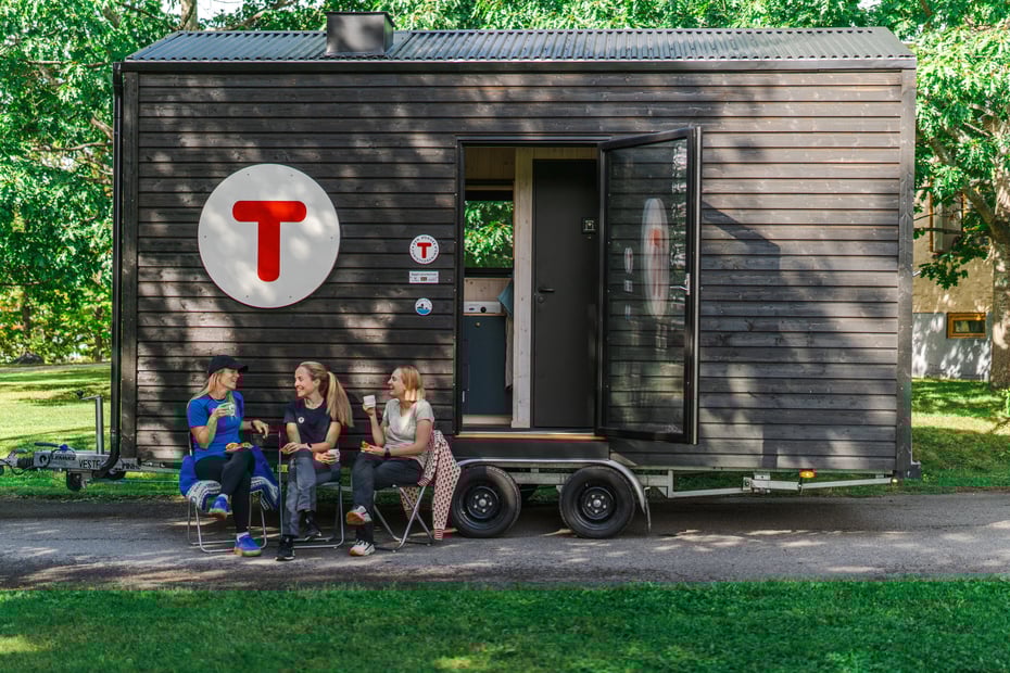 Tre damer sitter og drikker kaffe utenfor Hytta på hjul