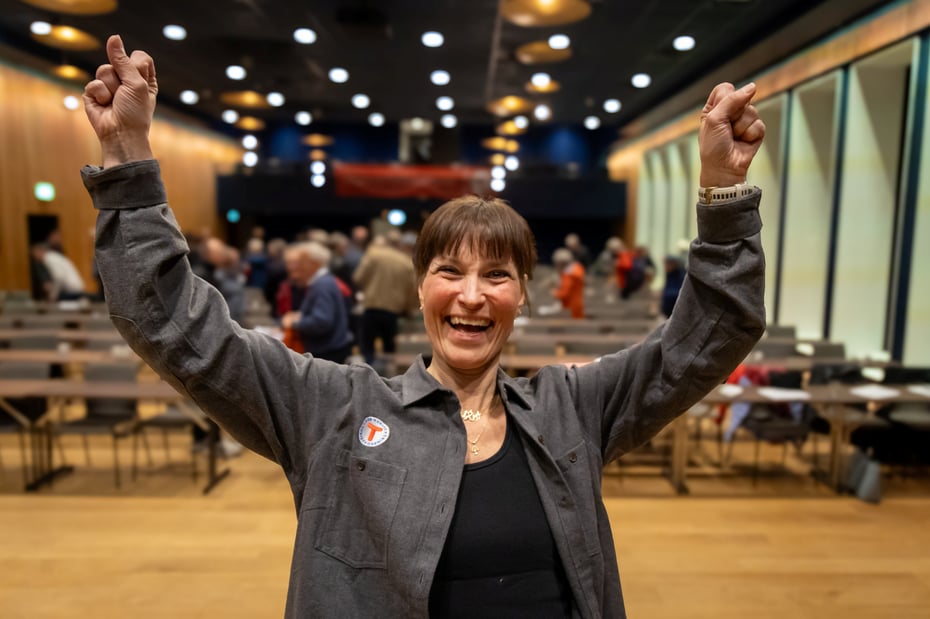 Dame jubler i en stor sal med folk bak.