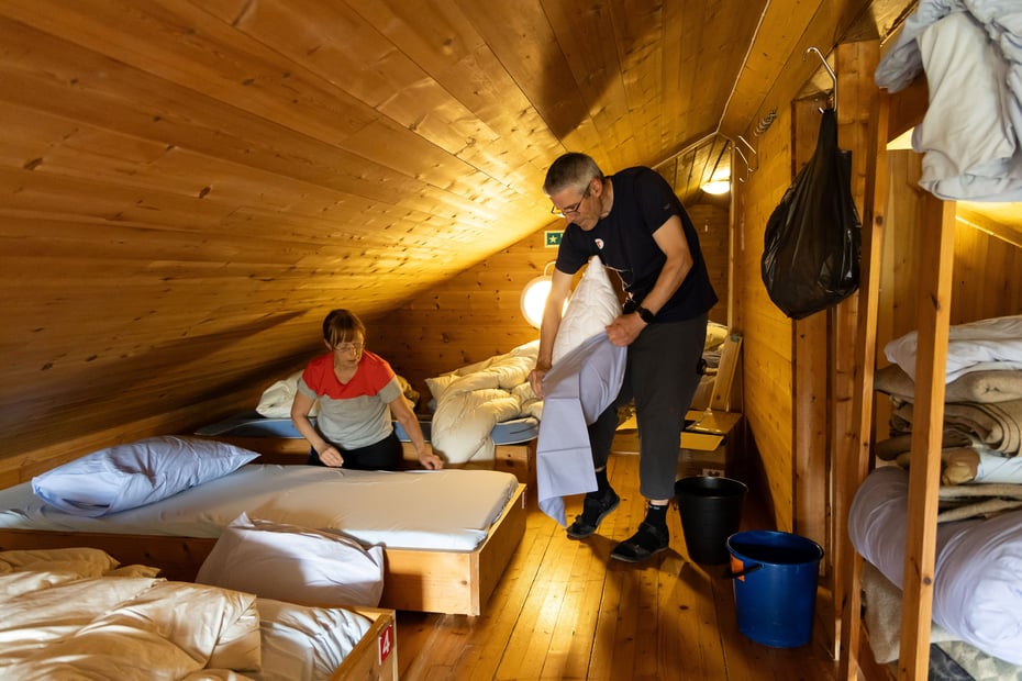 Mann og kvinne skifter sengetøy på hytte.