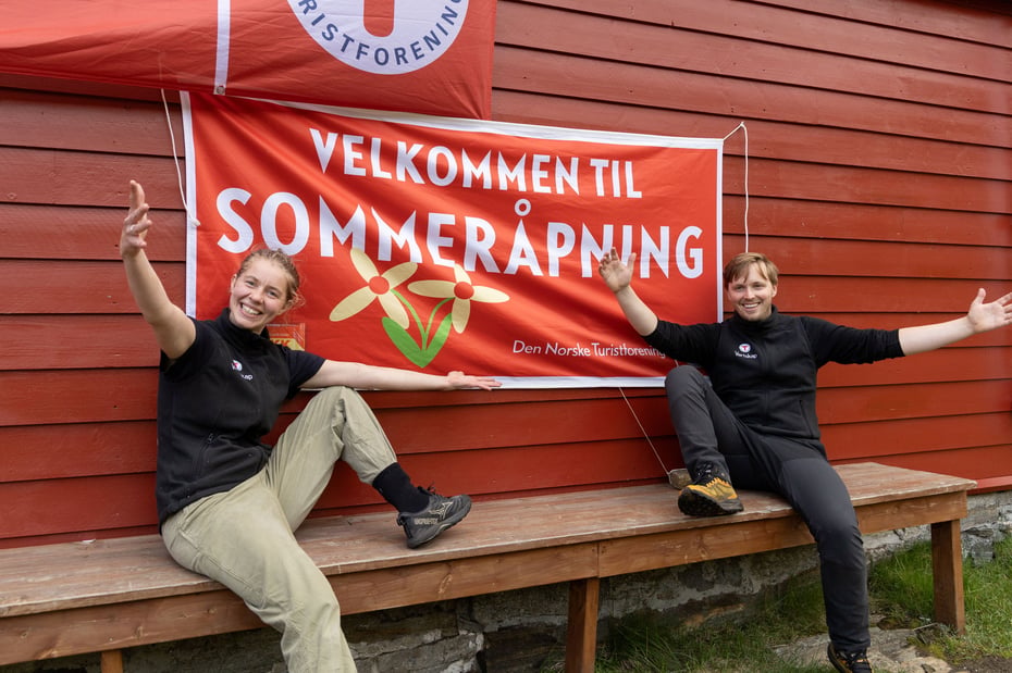 Mann og kvinne smiler med skilt det står Velkommen til sommeråpning på.