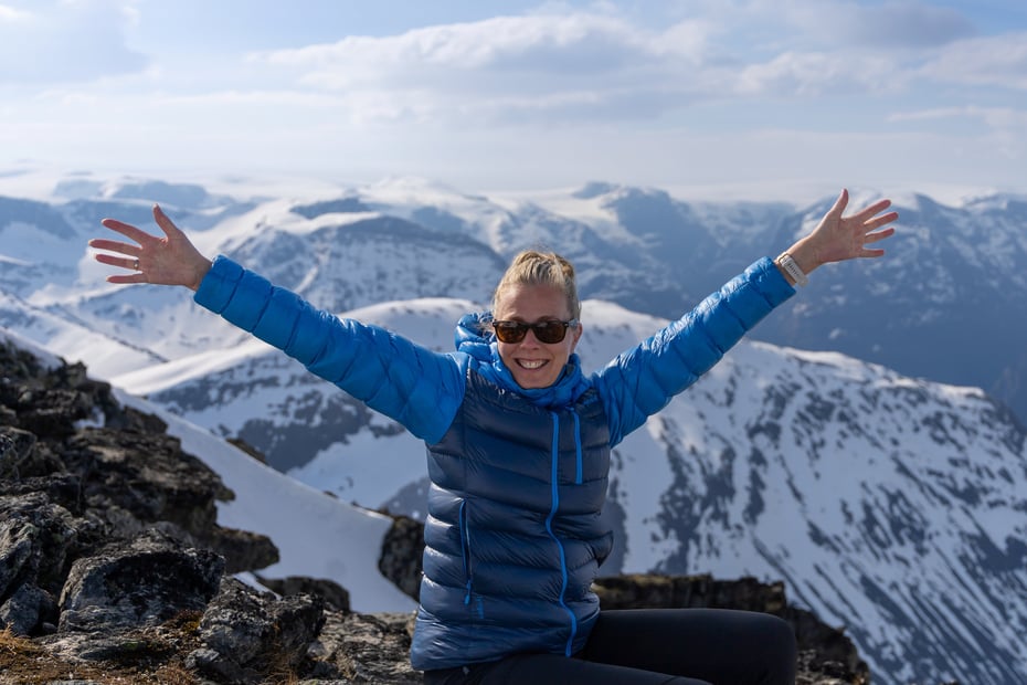 Dame med henden i været på fjelltopp.