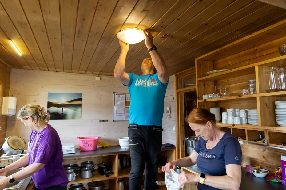 Tre personer holder på å rydde kjøkken som en del av dugnad for turlaget.