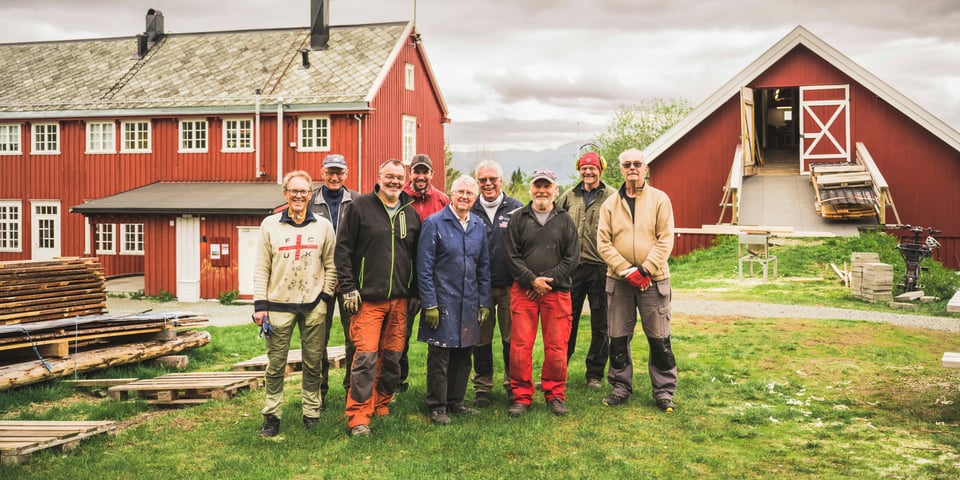 Gruppe mennesker foran rød hytte