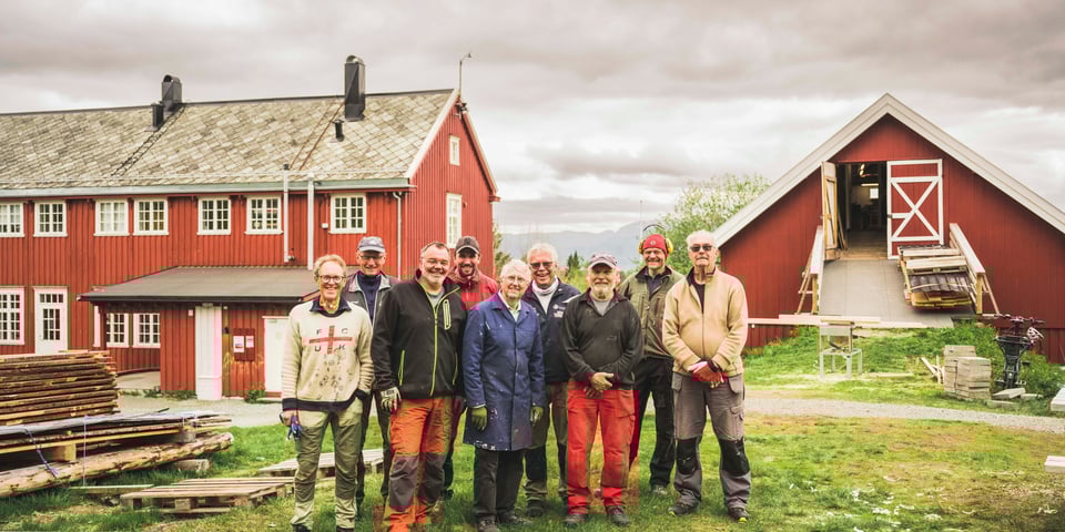 Gruppe mennesker foran rød hytte