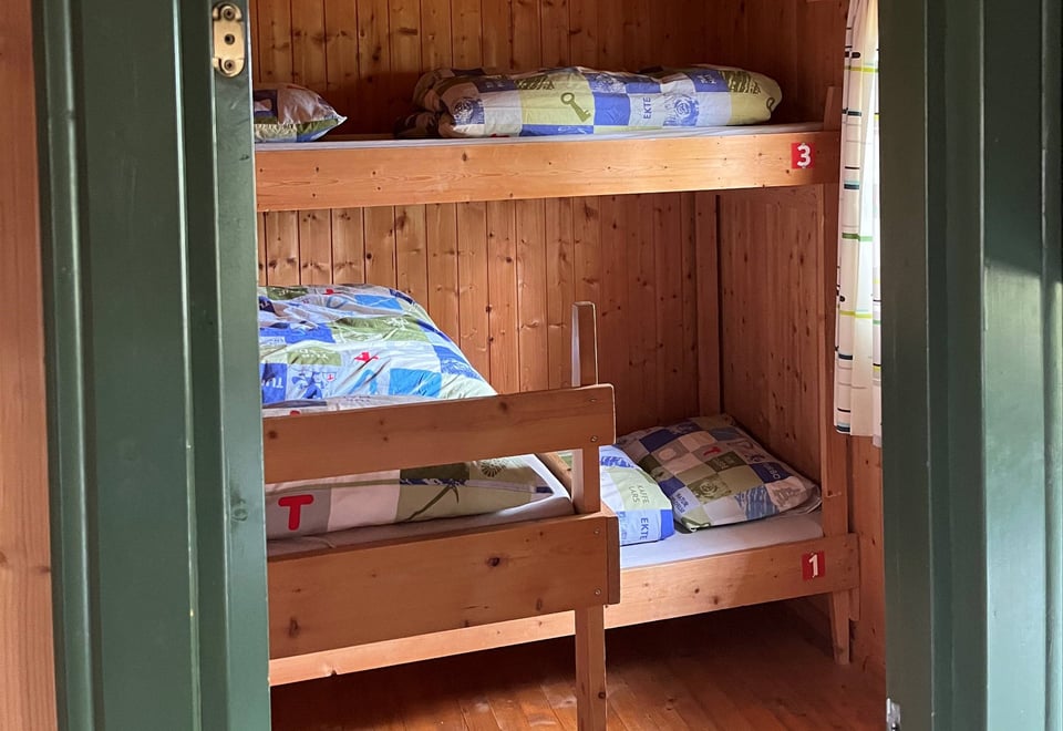 Døråpning med grønn ramme med innsyn til oppreide senger.