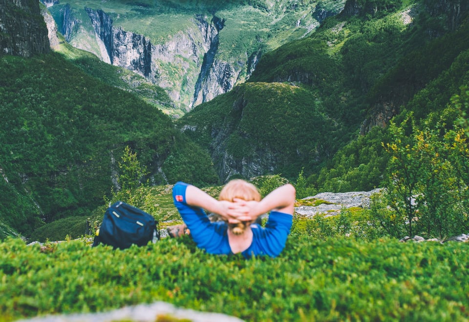 Mann ligger i lyngen og ser utover dal.
