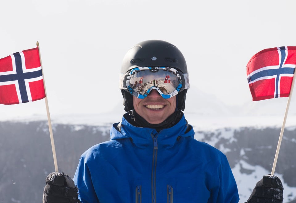 Flagging på Rasletind, en smilende fyr med skibriller og et norsk flagg i hver hånd.  