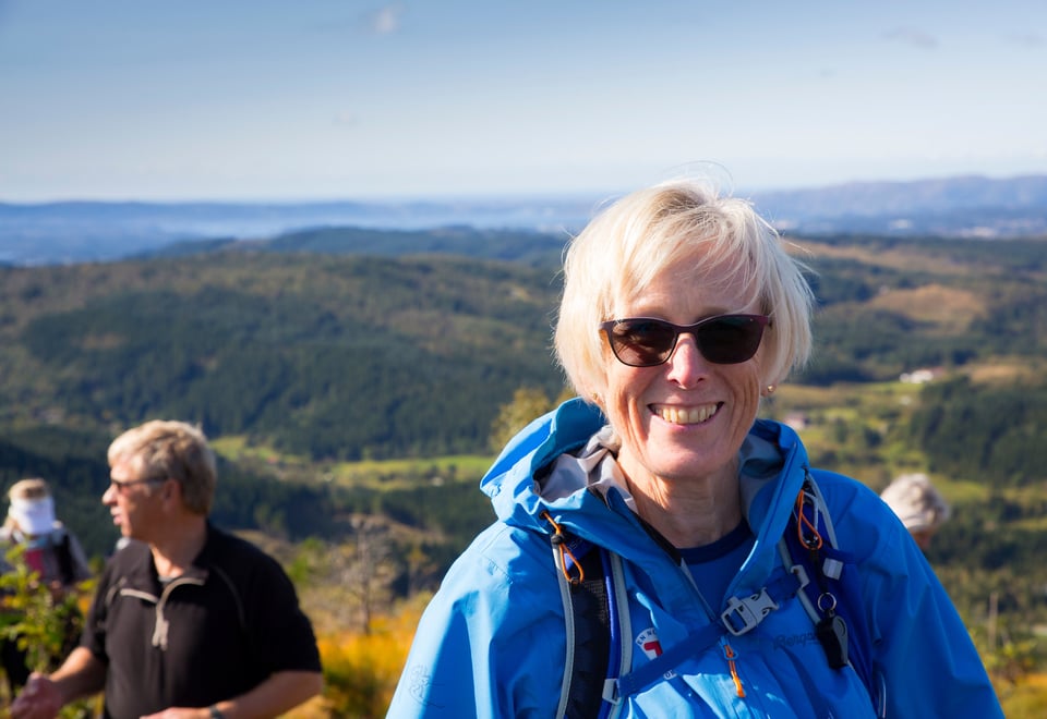 Kvinne på tur. Har på solbriller. Smiler. Foto 
