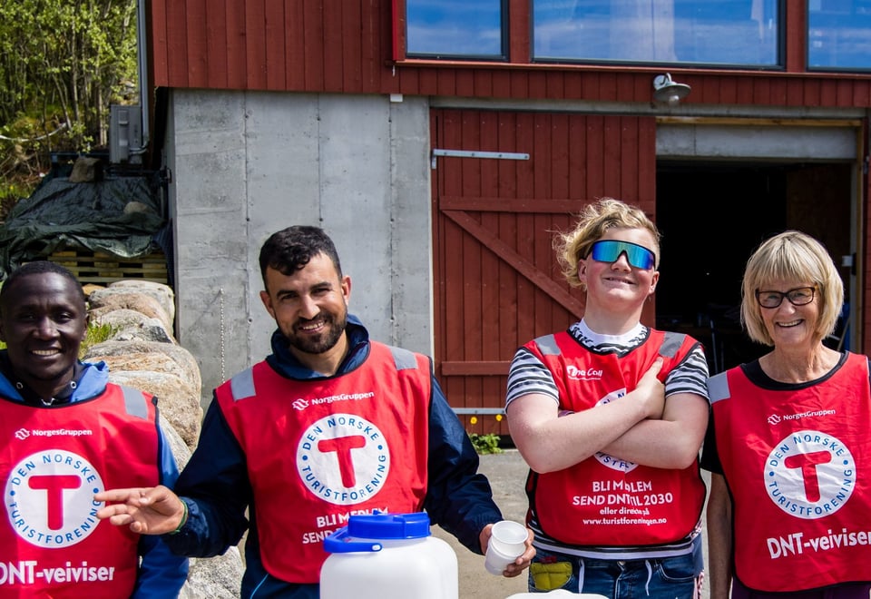 Smilende mennesker i røde vester med rød T på hvit bakgrunn smiler mot kamera 
