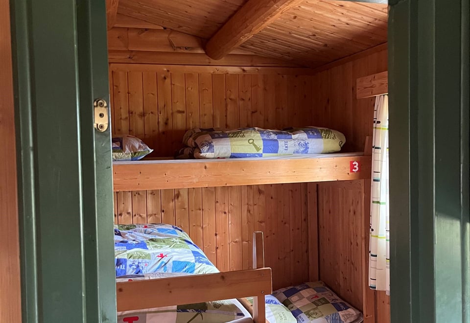 Døråpning med grønn ramme med innsyn til oppreide senger.