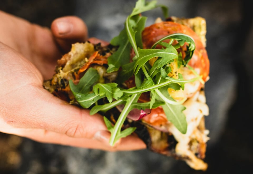 Hånd holder pizzastykke