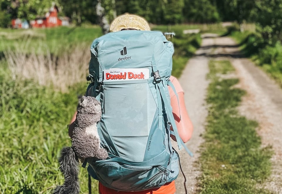 Barn med tursekk som går langs en landevei. Foto.