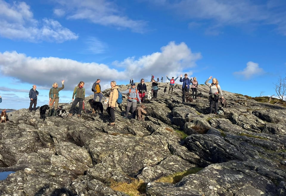 Mennesker samlet på fjelltopp. Sol og blå himmel 